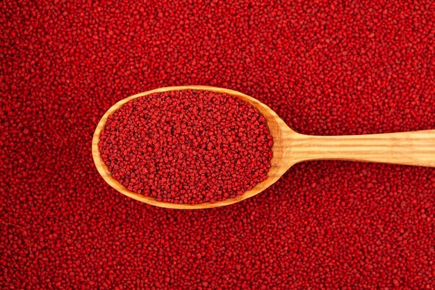 Organic Beetroot couscous in wooden spoon on of couscous background closeup