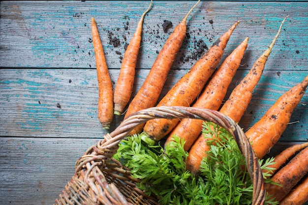 Organic carrots in wattled basket top view wooden