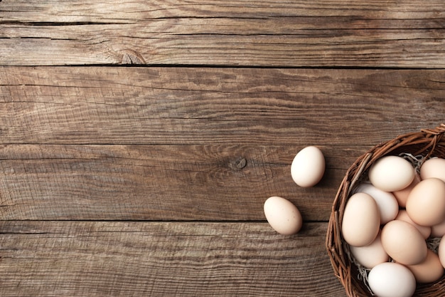 Organic chicken eggs in basket on wooden background. Organic household concept with eggs from free-range and pasture raised hens