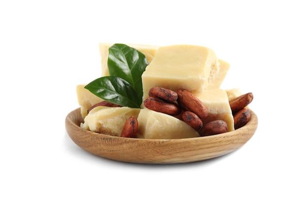 Organic cocoa butter beans and green leaves in wooden bowl isolated on white