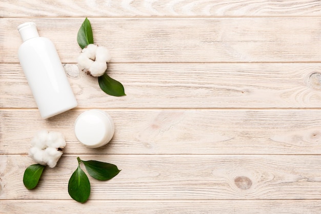 Organic cosmetic products with cotton flower and green leaves on wooden background Copy space flat lay