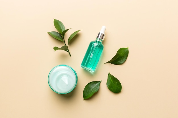 Organic cosmetic products with green leaves on color background. Flat lay.