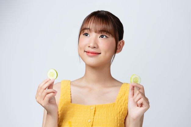 Organic cosmetics concept A young girl with clean skin holds cucumber slices near her face