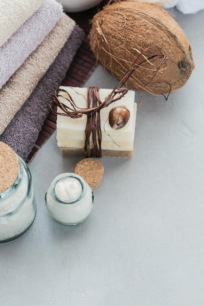 Organic cosmetics with coconut oil sea salt towels and handmade soap on grey background