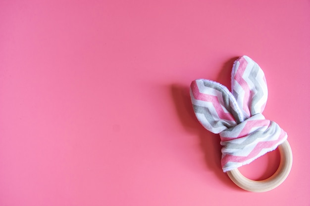 Organic cute baby bunny rabbit teether on pink background with copy space.