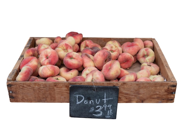 Organic Donut peaches in wooden crate with black color wooden price sign isolated on white