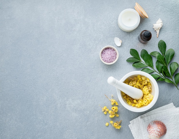 Organic dry flowers for the body and facial massager with sea salt creme candle and towel on a blue background Skin care The concept of a natural spa product Top view and copy space