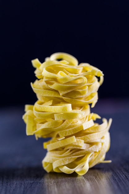 Organic fettuccine nests pasta on wood board.