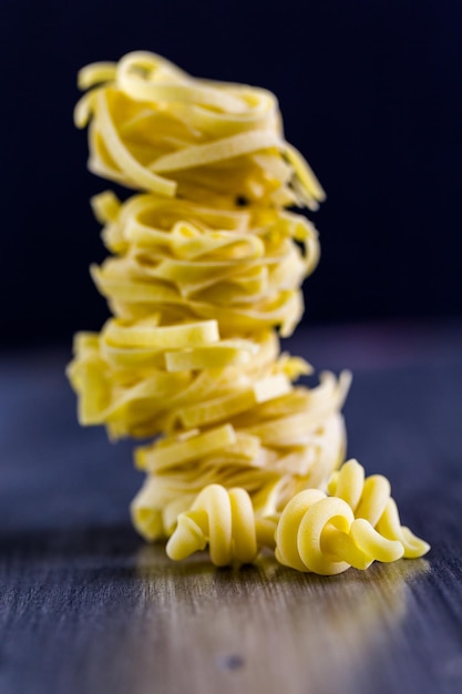 Organic fettuccine nests pasta on wood board.