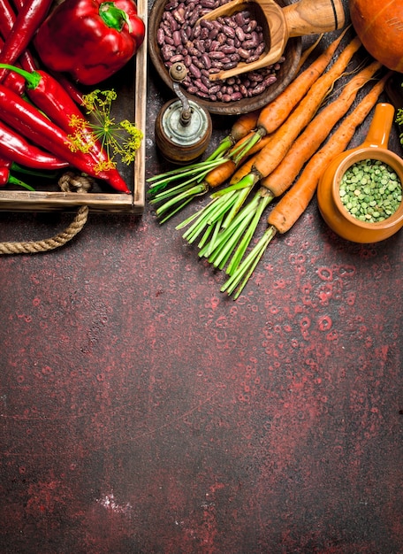 Organic food. Fresh crop of legumes and vegetables. On a rustic background.