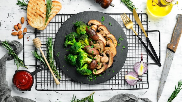 Organic food Fried mushrooms and broccoli on a black stone plate Rustic style Top view