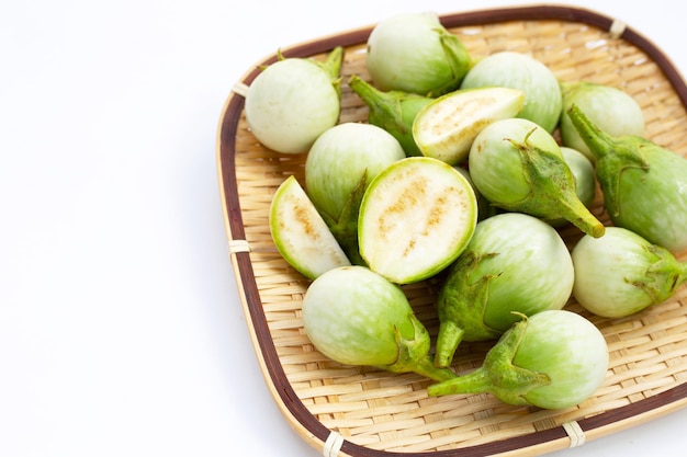 Organic green eggplant in bamboo basket on white background.