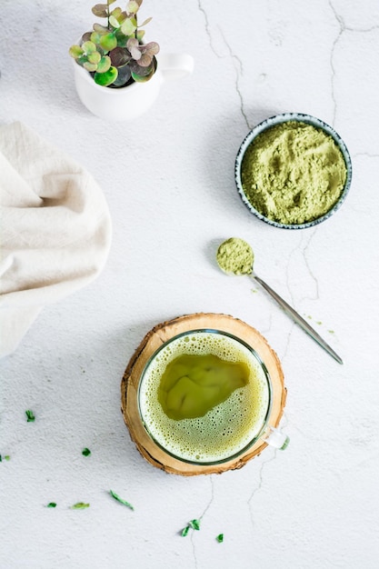 Organic green matcha tea in a cup on a tree trunk on the table Source of vitamins and antioxidants Top and vertical view