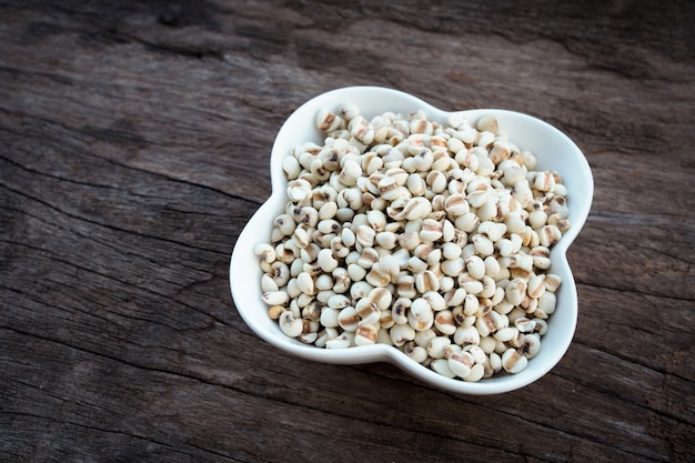 Organic millet grains on white bowl on old wooden table.