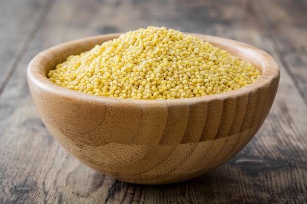 Organic millet seeds in wooden bowl on wooden table