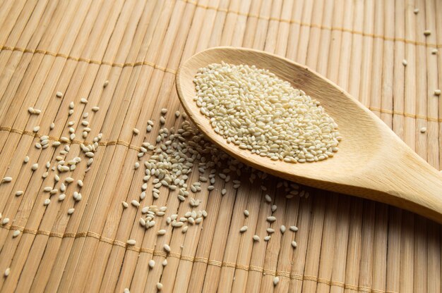 Organic natural sesame seeds on wooden spoon and bamboo napkin