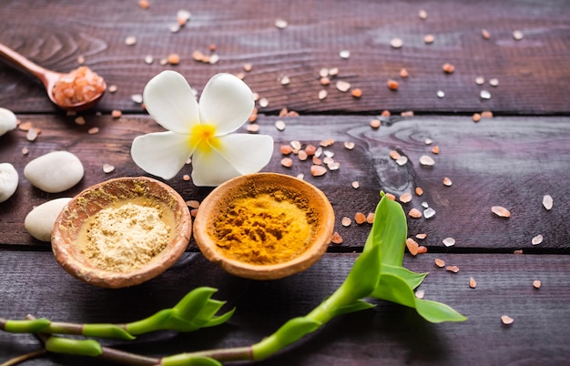 Organic pure Powder Turmeric and Tanaka clay cup with fresh frangipani flowers perfumeryhimalaya salt on wooden background ancient herb herbal of thailand Aromatherapy Spa setmassage oriental