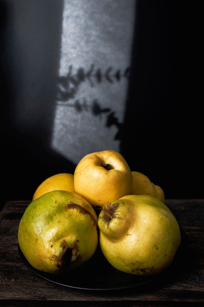 Photo organic and ripe quinces on a wooden kitchen table dark mood food photography