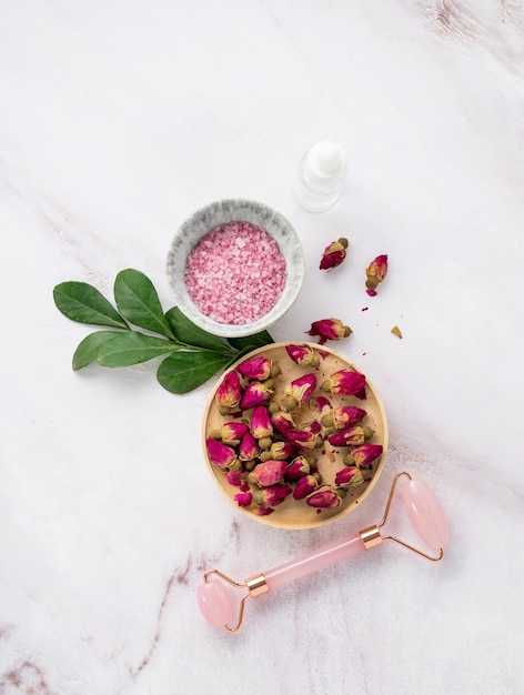 Organic sea salt for the body with dried rose flowers and gua sha on a pink marble background Skin care The concept of a natural spa product Top view and copy space