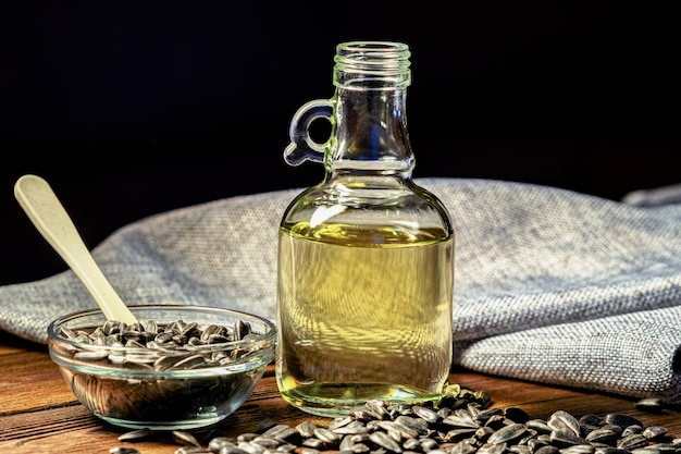 Organic sunflower oil in a small glass jar. Close-up photo of sunflower oil with seeds on a wooden background. The concept of a bio- and organic product.