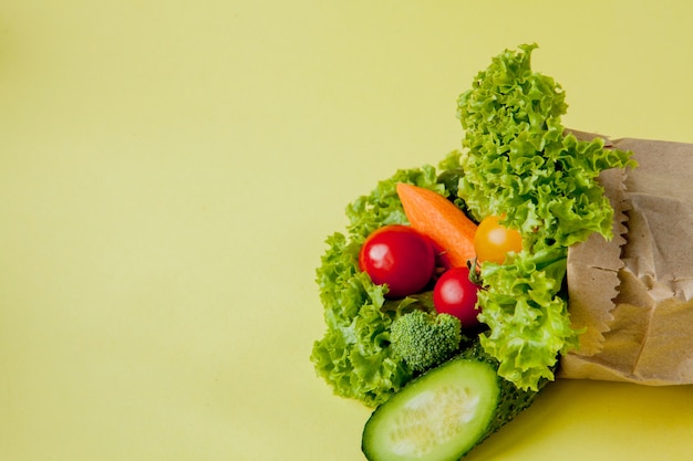 Organic vegetables broccoli cucumbers bell peppers apples in brown paper Kraft grocery bag