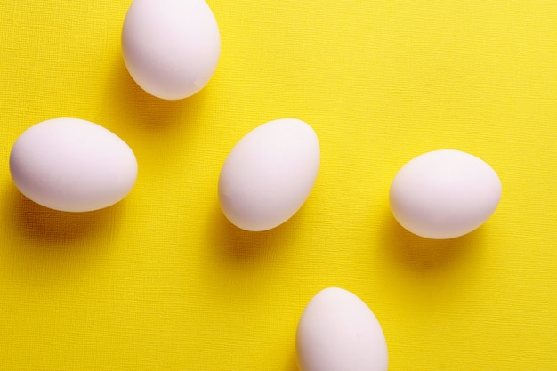 Organic white eggs in a raw on yellow backgound. 