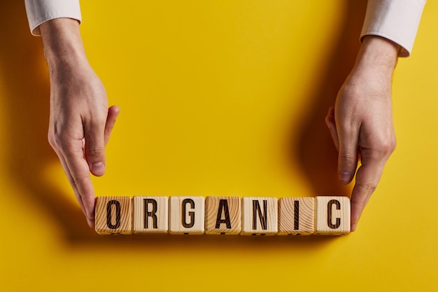 Photo organic word on a yellow background written on a wooden block organic text on the table concept