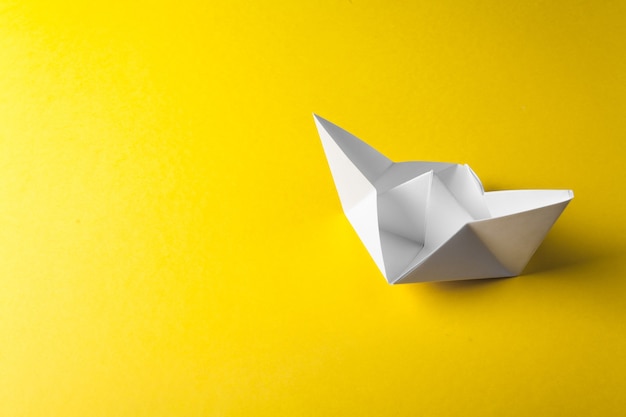 Origami boat paper on the yellow surface