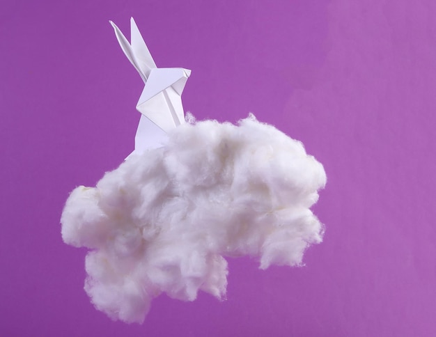 Origami bunny with fluffy cloud on purple background Creative easter idea Minimal concept