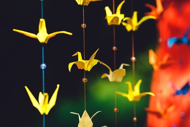 Origami from colored paper in the form of cranes hanging on a string. Wedding decor of colored paper.