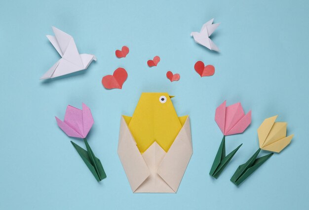 Origami spring composition of chicken tulips and doves on a blue background Spring easter concept