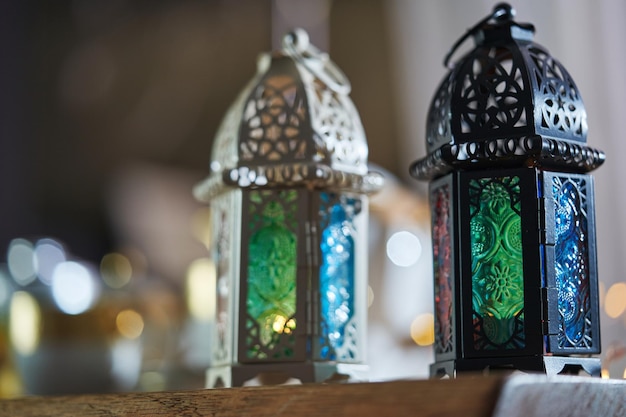 Ornamental Arabic lantern with burning candle glowing and beautiful tea set as background