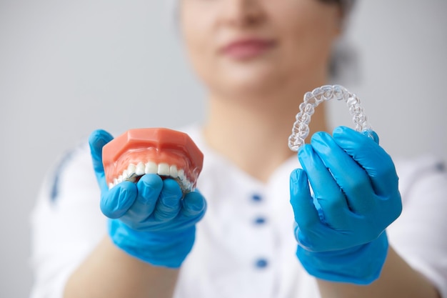 Orthodontist showing model of human jaw with wire braces and aligners explaining the difference