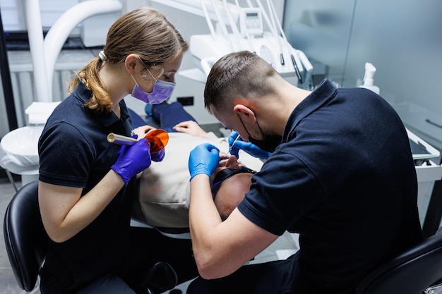 An orthodontist with an assistant treats teeth using dental instruments Dental office Orthodontic treatment of teeth