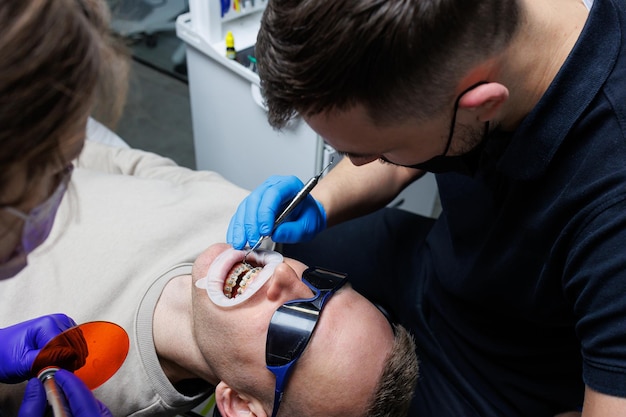 An orthodontist with an assistant treats teeth using dental instruments Dental office Orthodontic treatment of teeth