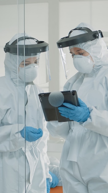 Orthodontists wearing protection suits looking at tablet