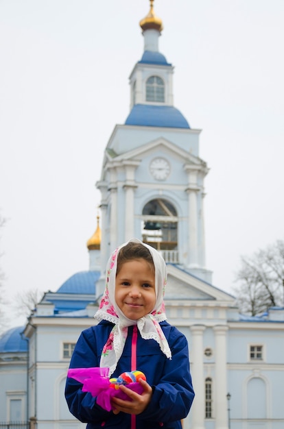 Orthodox Easter. Girl with colored Easter eggs over the church