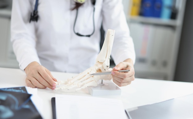 Photo orthopedic doctor show human plastic feet model analyzing every bone and toe