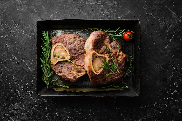 Osso buco cooked Veal shank with spices and rosemary Barbecue meat Top view Flat lay top view on black stone cutting table