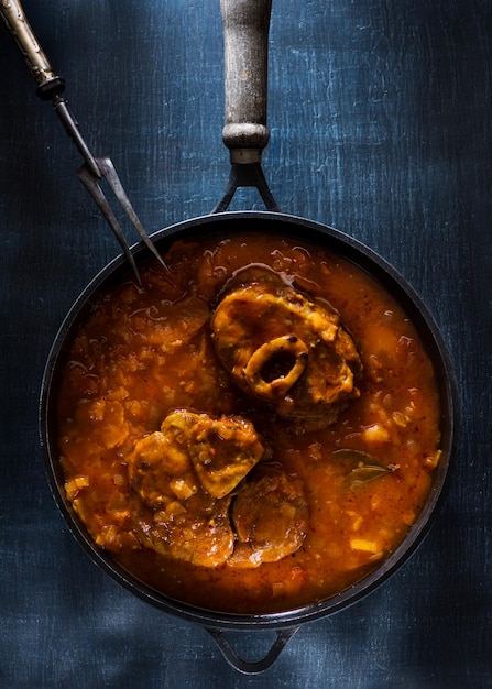 Photo osso buco veal shanks prepared with tomatoes, carrots and onions in a cast-iron pan