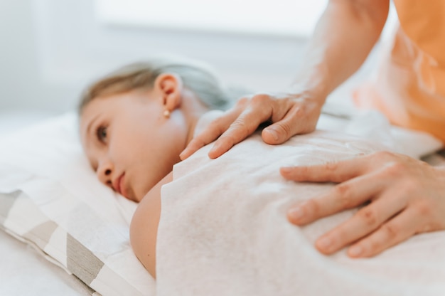 osteopath hands does therapy for girl. pediatric osteopathy treatment session. alternative medicine