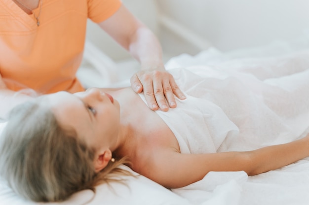 osteopath hands does therapy for girl. pediatric osteopathy treatment session. alternative medicine