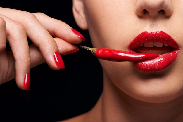 The other forbidden fruit Closeup of a woman holding a red chilli to her mouth