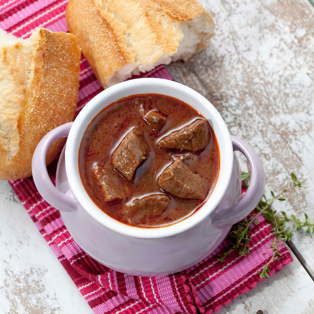 Oulash soup with white bread in bowl, close up