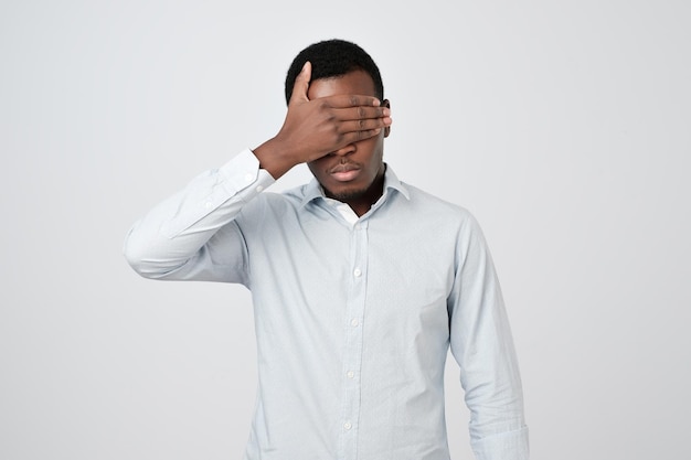 Oung african man in white shirt covering eyes