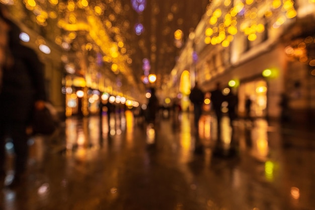 Out of focus cityscape with silhouettes of people surrounded by blurry lights of New Year decoration