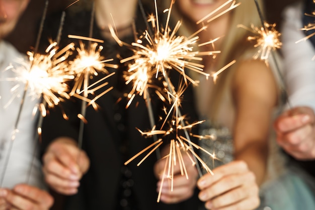 Out of focused image of party people with burning sparklers celebrating  holiday or event