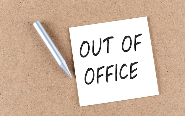 OUT OF OFFICE text on sticky note on a cork board with pencil