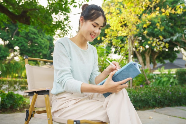 Outdoor activity concept Female artist sitting in the garden and drawing picture on digital tablet