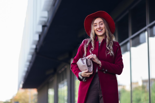 Outdoor autumn portrait of young elegant fashionable woman wearing trendy coat look at camera